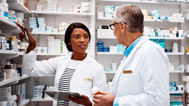 Two pharmacists review drug inventory